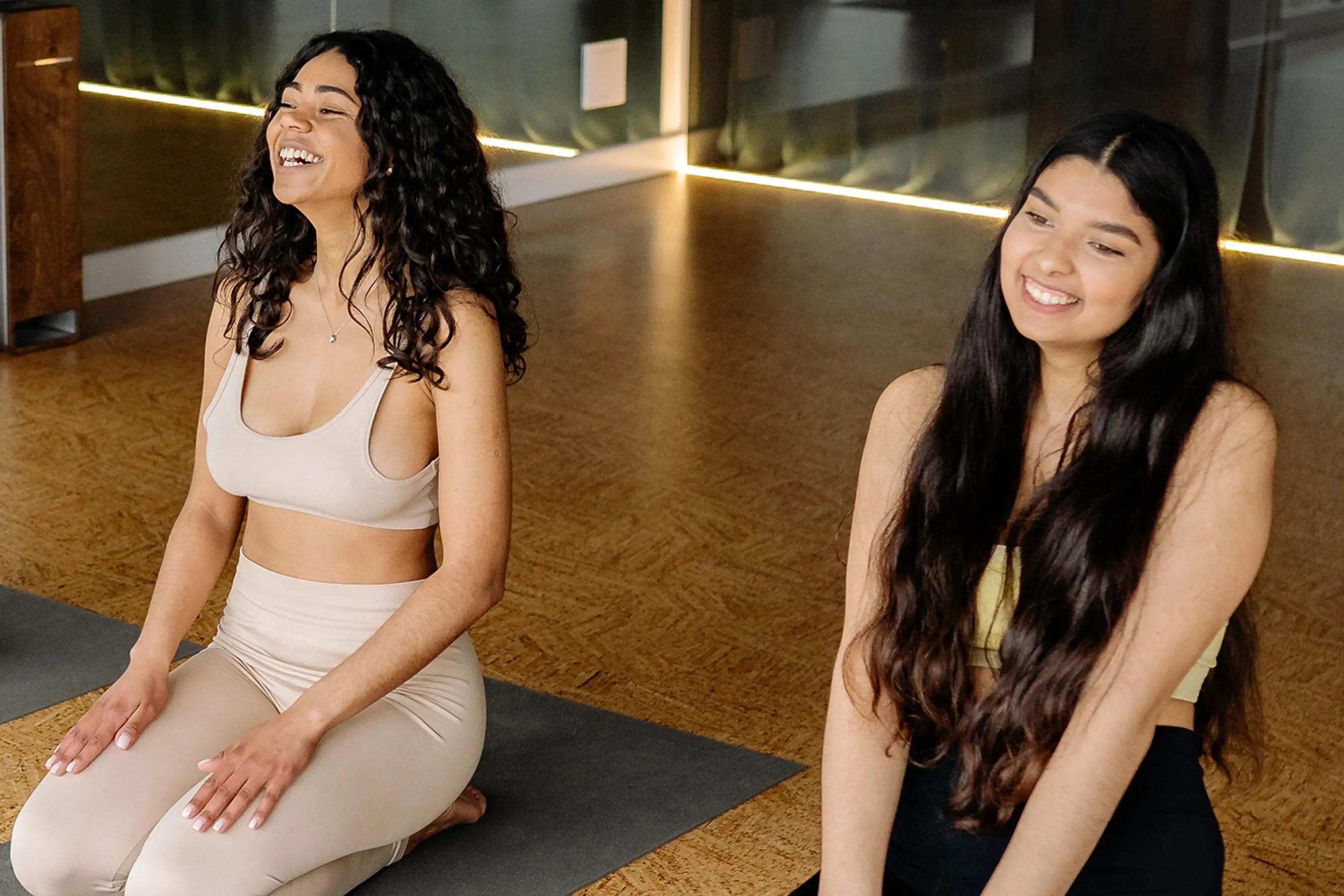 two women sitting on yoga mats, in a yoga studio